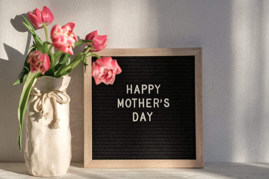Pink flowers wrapped in a fabric bag. Black board next to flowers that reads Happy Mother's Day
